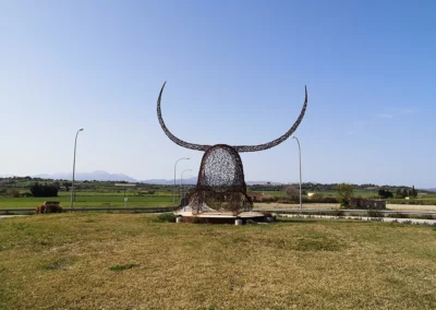 "Imponente escultura de hierro del Cap de Dimoni en la entrada de Santa Margalida, Mallorca." "Monumental obra del Cap de Dimoni, emblema de la tradición y la artesanía de Santa Margalida." "La Escultura del Cap de Dimoni en Santa Margalida, un punto de encuentro cultural en Mallorca." "Vista de la escultura del Cap de Dimoni en Santa Margalida, reflejo de las fiestas de la Beata." "El Cap de Dimoni de Santa Margalida, un hito artístico forjado en hierro en el corazón de Mallorca."