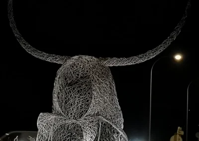 "Imponente escultura de hierro del Cap de Dimoni en la entrada de Santa Margalida, Mallorca." "Monumental obra del Cap de Dimoni, emblema de la tradición y la artesanía de Santa Margalida." "La Escultura del Cap de Dimoni en Santa Margalida, un punto de encuentro cultural en Mallorca." "Vista de la escultura del Cap de Dimoni en Santa Margalida, reflejo de las fiestas de la Beata." "El Cap de Dimoni de Santa Margalida, un hito artístico forjado en hierro en el corazón de Mallorca."v