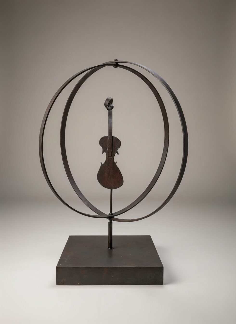 Escultura de gran formato Órbita interior en hierro corten, composición circular con forma central suspendida inspirada en el violín, equilibrio entre movimiento y vacío sobre base metálica.