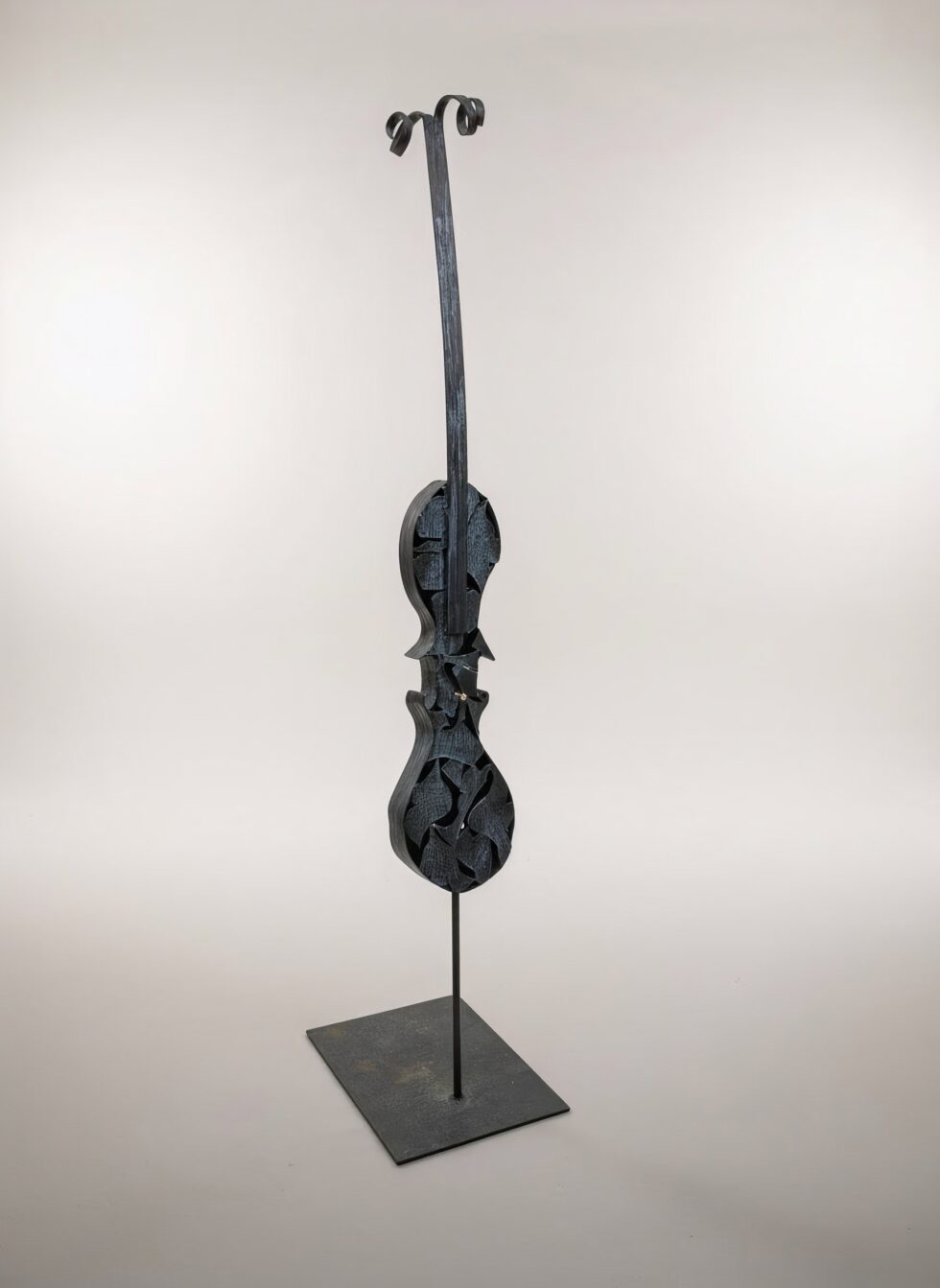 Escultura de gran formato Silenci en ferro en hierro patinado, composición vertical inspirada en el violín con formas interiores recortadas, sobre base metálica.