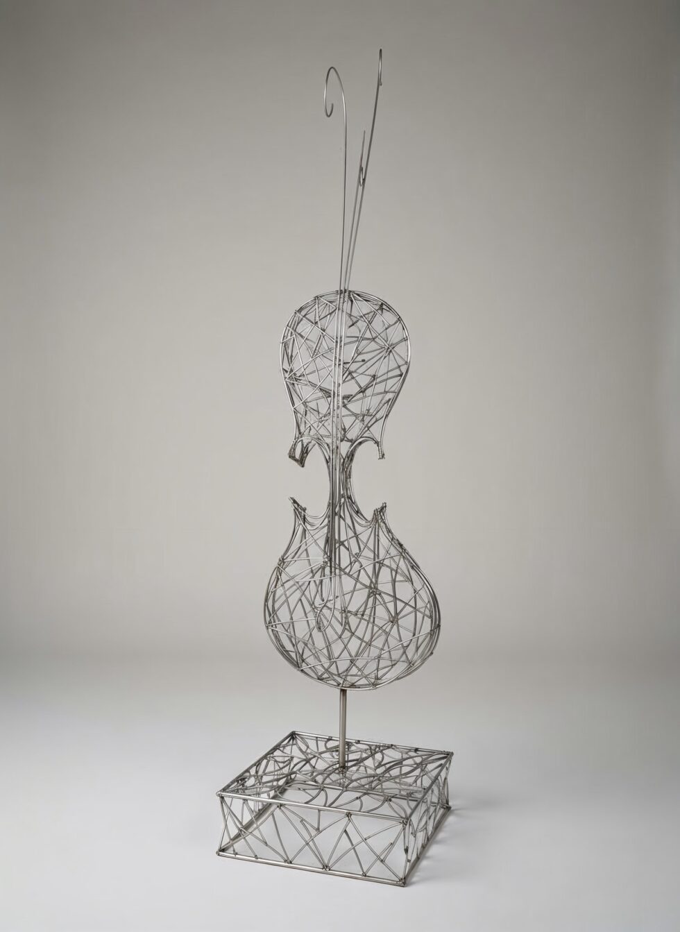 Escultura de gran formato Traç a l’aire en acero inoxidable, estructura abierta de líneas metálicas inspirada en la forma del violín, sobre base geométrica.